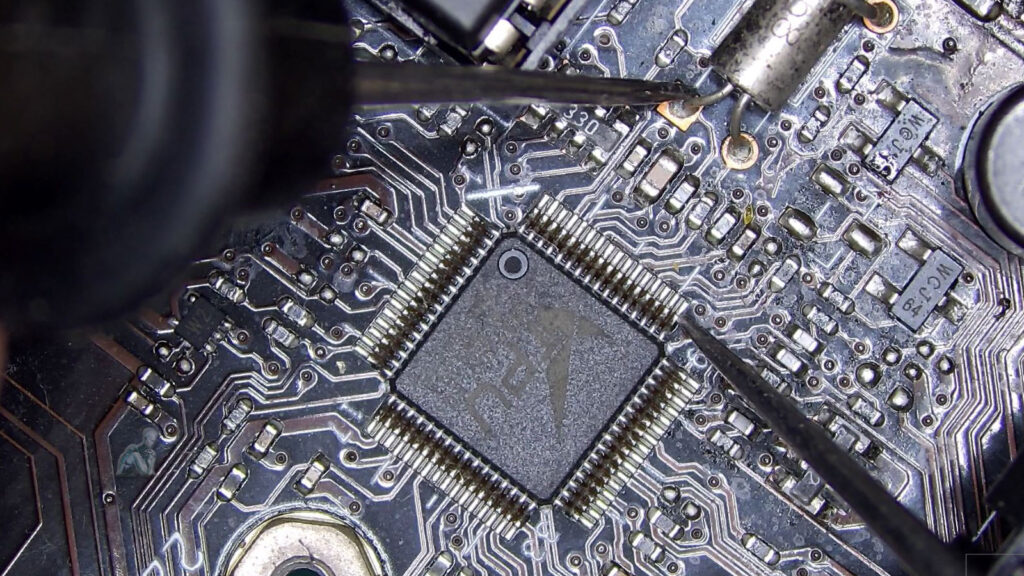 Multimeter probes measuring resistance at a crystal oscillator on a circuit board, indicating potential signal failure during diagnostic testing