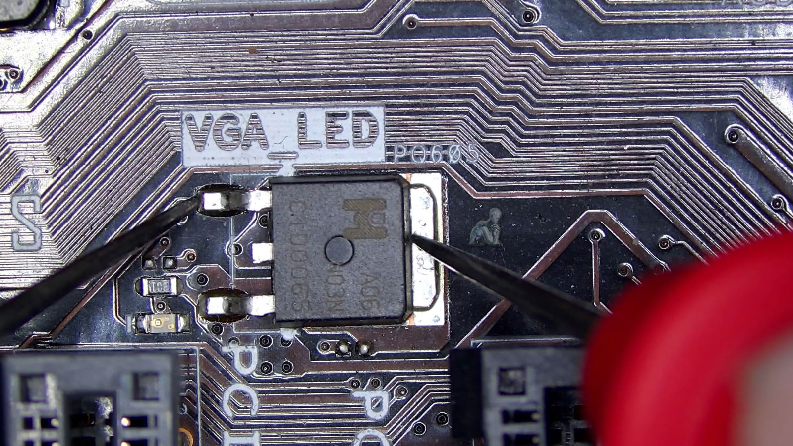 Multimeter measuring a transistor near a VGA LED indicator on a motherboard to locate a short circuit preventing the system from powering on
