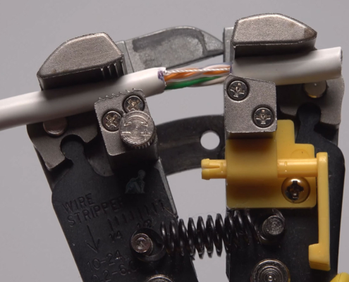 CAT6 network cable being stripped with a tool to prepare wires for RJ45 connector termination