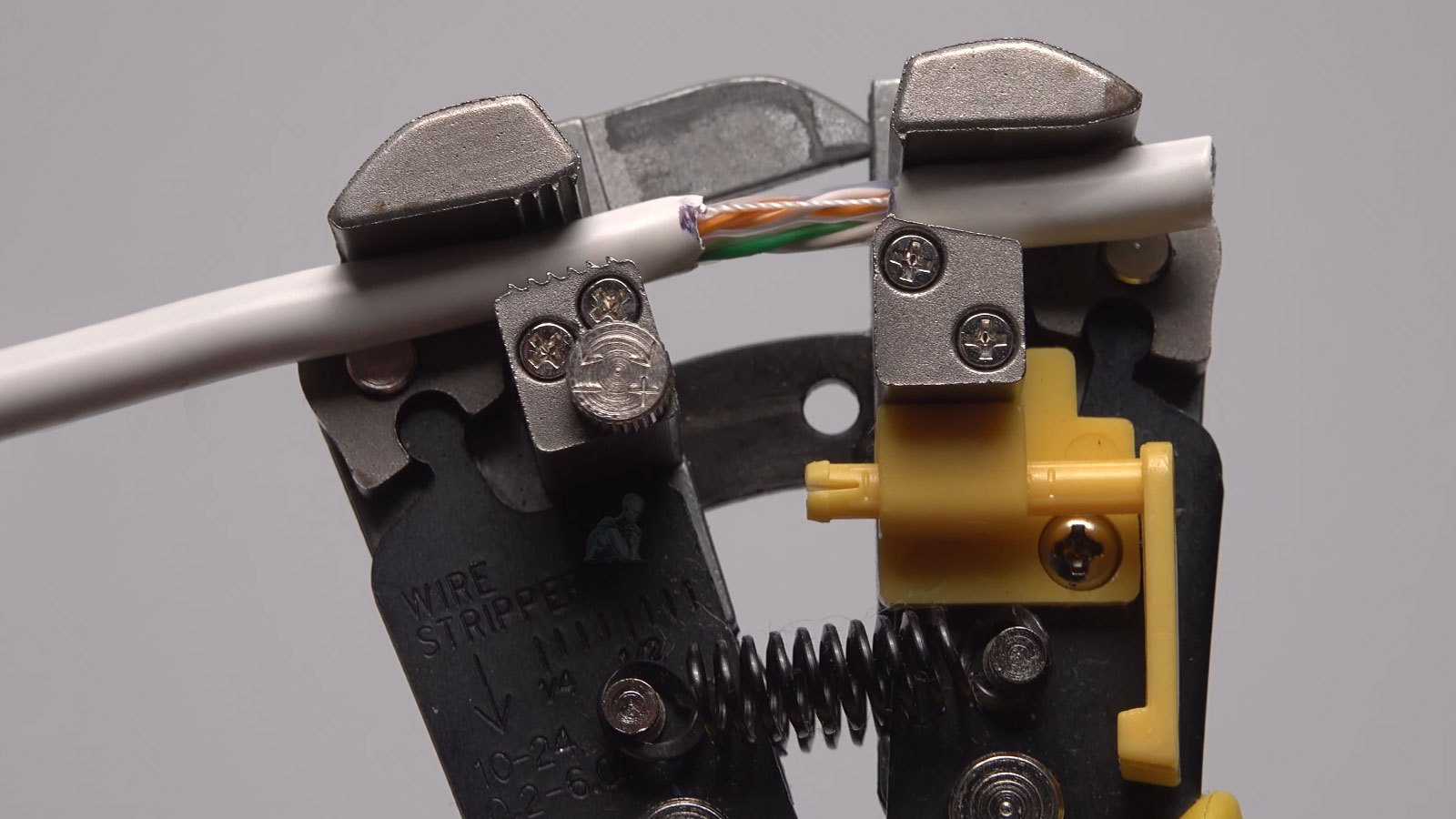 CAT6 network cable being stripped with a tool to prepare wires for RJ45 connector termination
