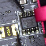 Multimeter measuring resistance between an IC chip and a large 205K resistor on a circuit board during diagnostic testing