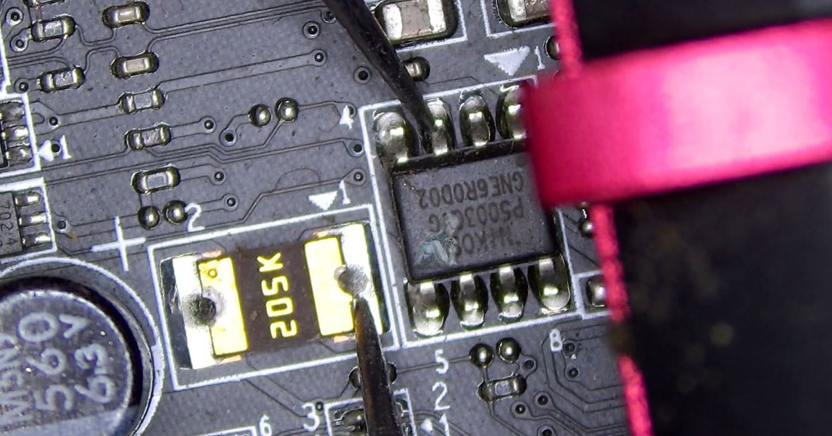 Multimeter measuring resistance between an IC chip and a large 205K resistor on a circuit board during diagnostic testing
