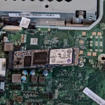 Back panel of an all-in-one computer opened while installing a new M.2 SSD into the motherboard slot