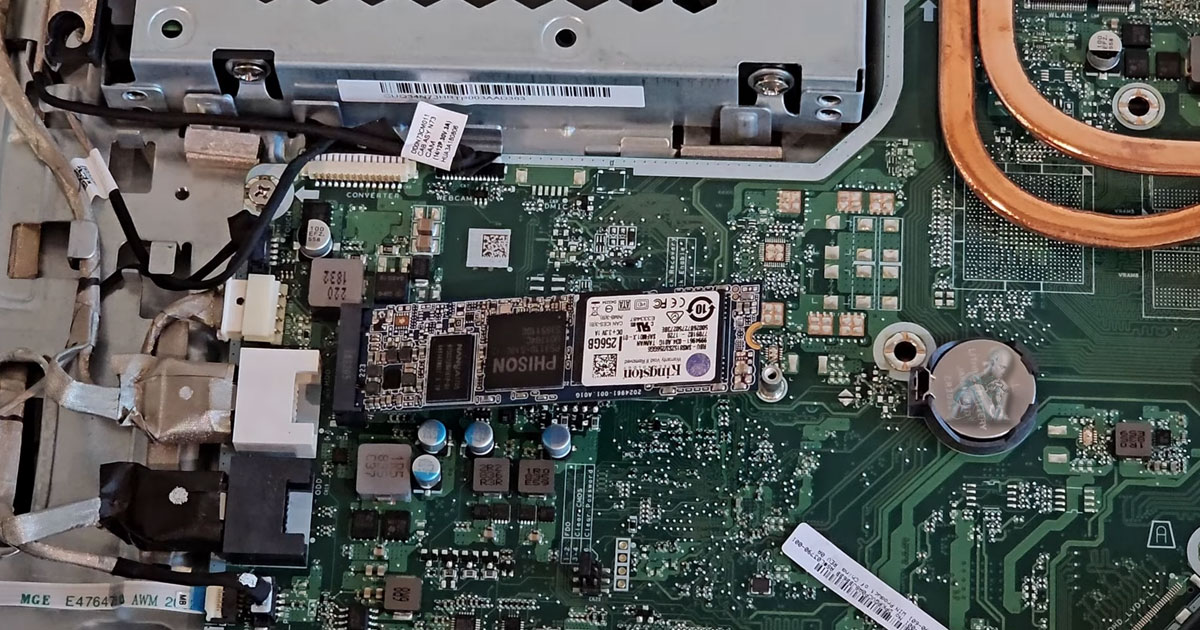 Back panel of an all-in-one computer opened while installing a new M.2 SSD into the motherboard slot