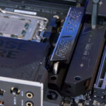 Technician installing a motherboard into a computer case while assembling a custom gaming PC with surrounding components visible