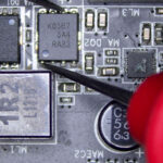 Multimeter probes testing a MOSFET on a gaming console circuit board to analyze electrical behavior during diagnostics