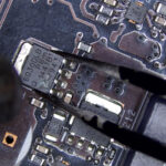 Technician using a hot air rework station to remove a damaged component from a GPU during board-level repair