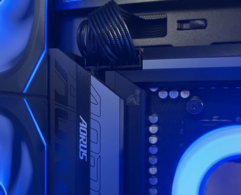 AORUS gaming PC with blue LED cooling fans actively running, showing internal components and illuminated system performance setup