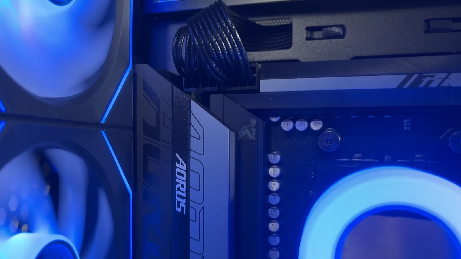 AORUS gaming PC with blue LED cooling fans actively running, showing internal components and illuminated system performance setup
