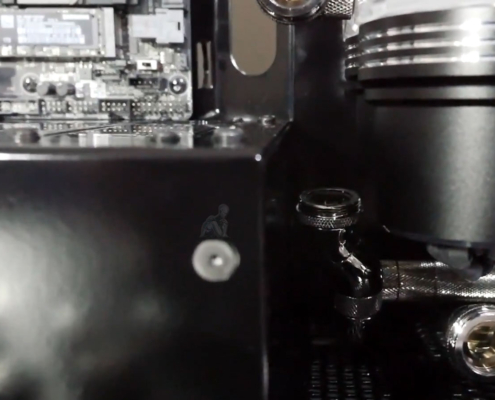 Custom-built PC with hard tube liquid cooling system open during repair, showing fittings being removed after a water leak