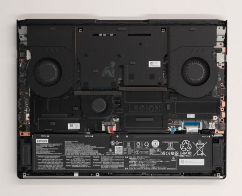 Legion gaming laptop with back cover removed showing internal components, dual cooling fans, heat pipes, and dust buildup for maintenance inspection
