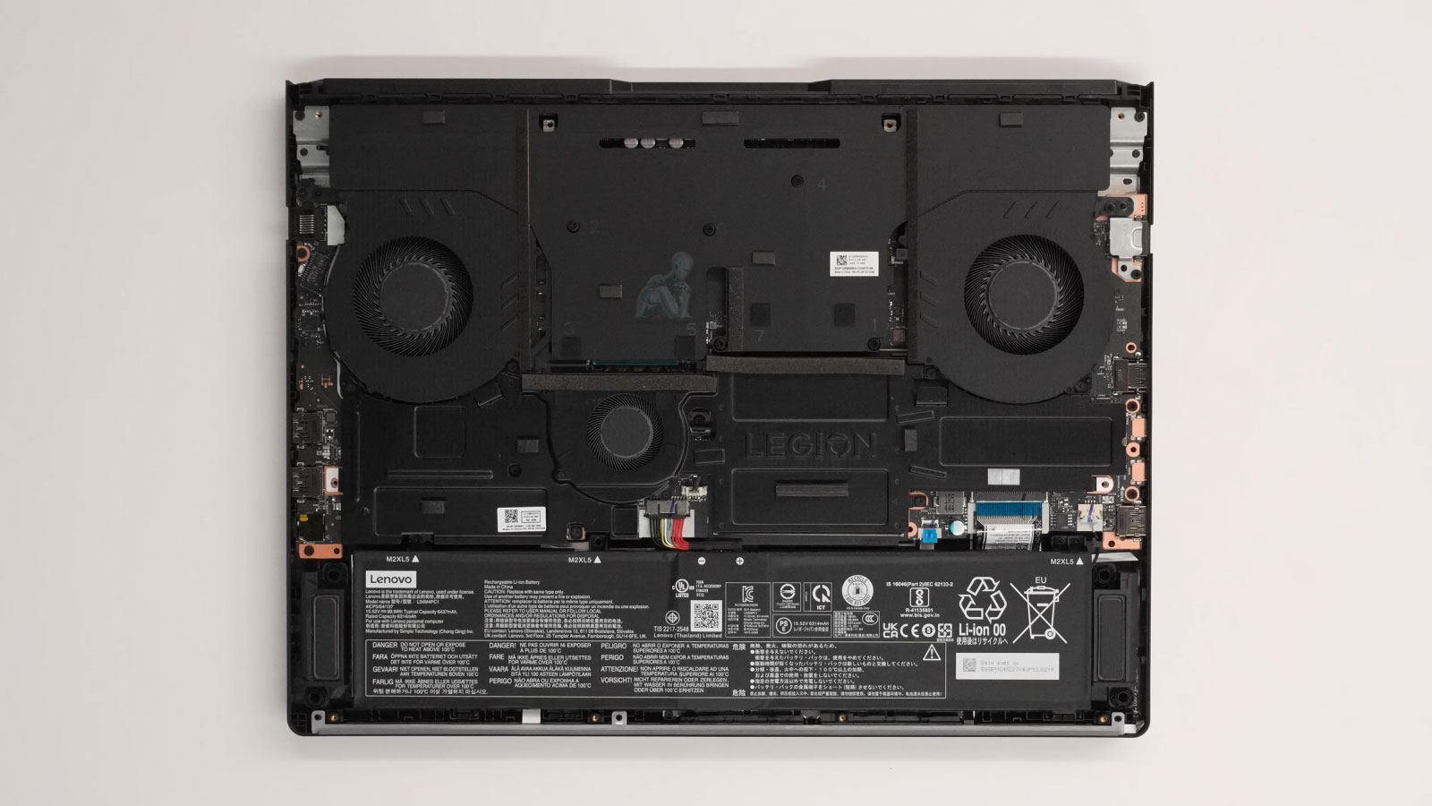 Legion gaming laptop with back cover removed showing internal components, dual cooling fans, heat pipes, and dust buildup for maintenance inspection