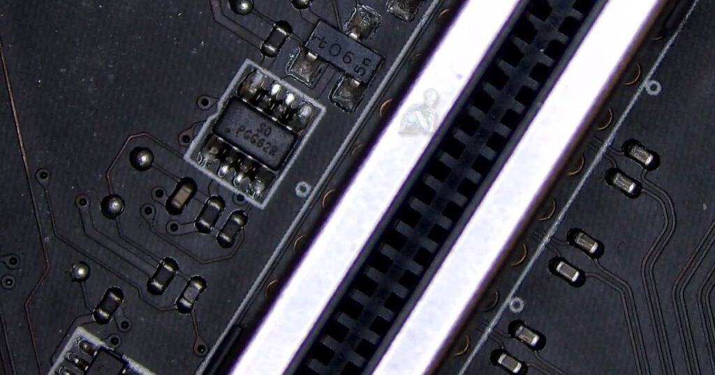 Close-up of a small surface-mounted IC on a motherboard near RAM slots, identified as defective and affecting memory detection and operation