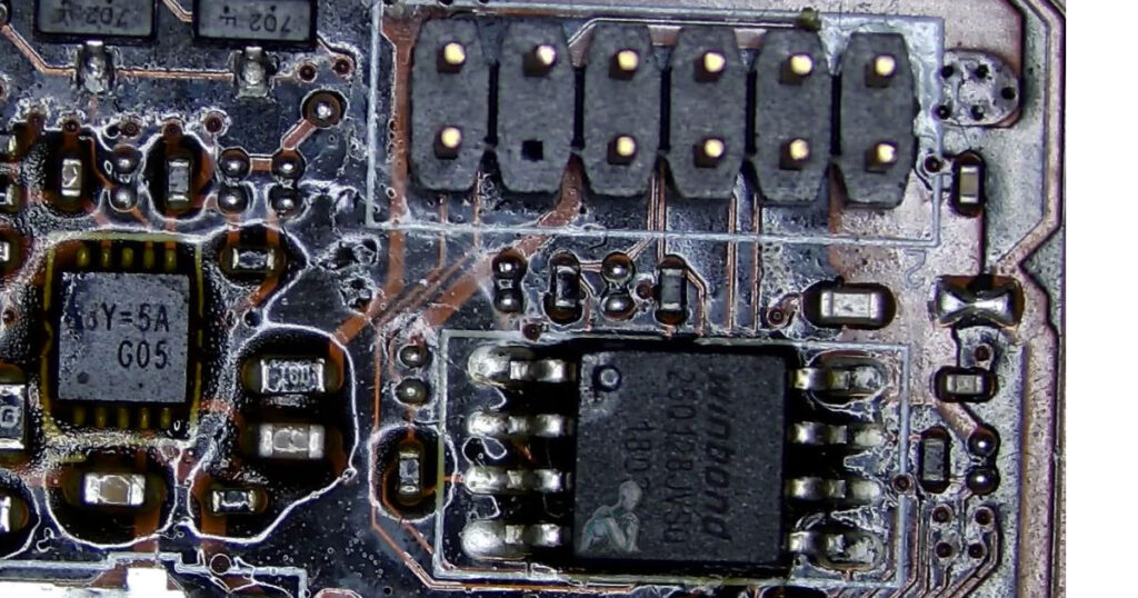 Winbond BIOS chip on a motherboard surrounded by flux during active soldering work, showing detailed chip-level intervention