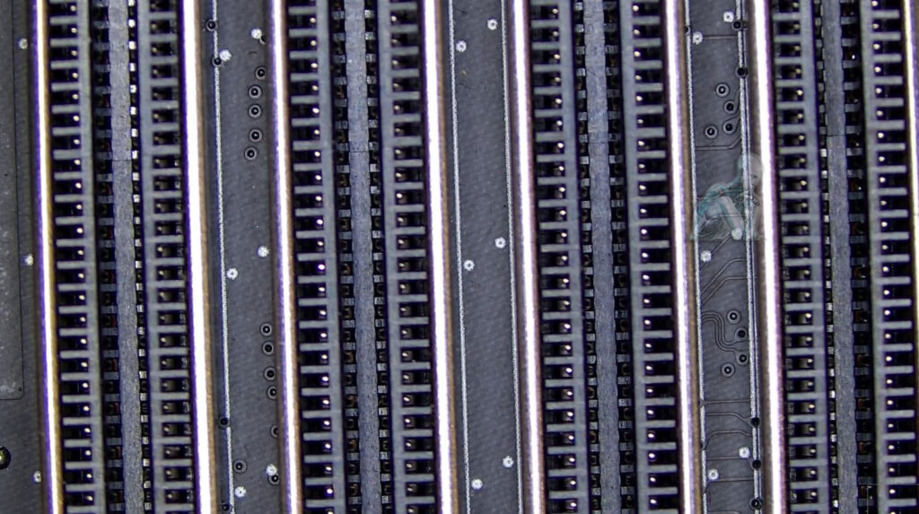 Close-up of motherboard memory slots being examined for internal damage, with attention to contact points and structural condition inside the connectors