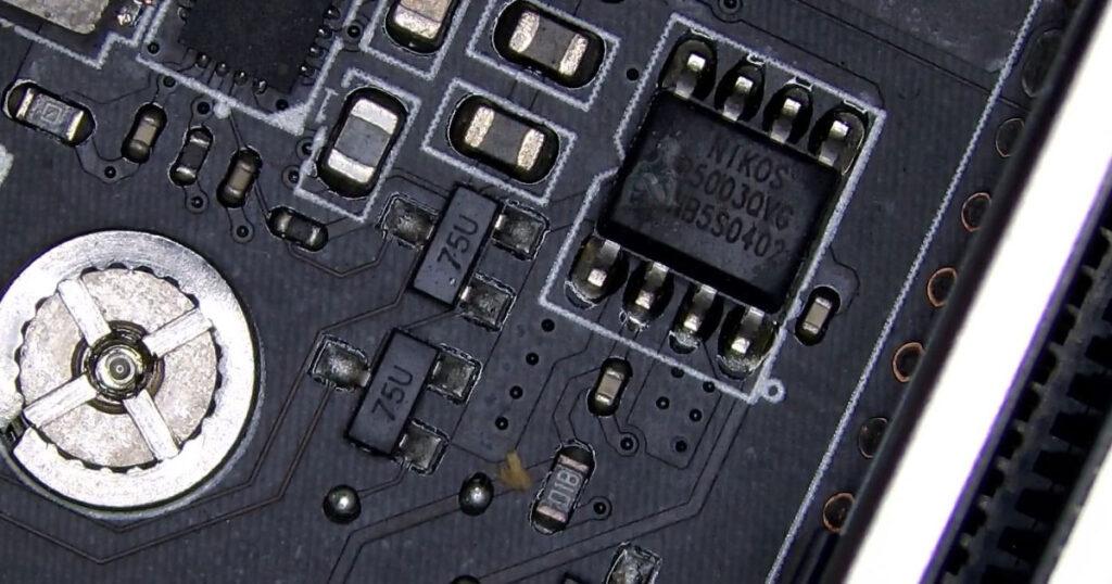 Damaged NIKOS MOSFET on MSI motherboard showing heat stress near the VRM section with surrounding surface-mounted components visible