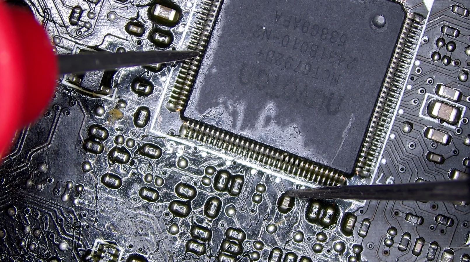Motherboard under inspection with multimeter probes checking a ground short condition across components on a densely populated circuit board
