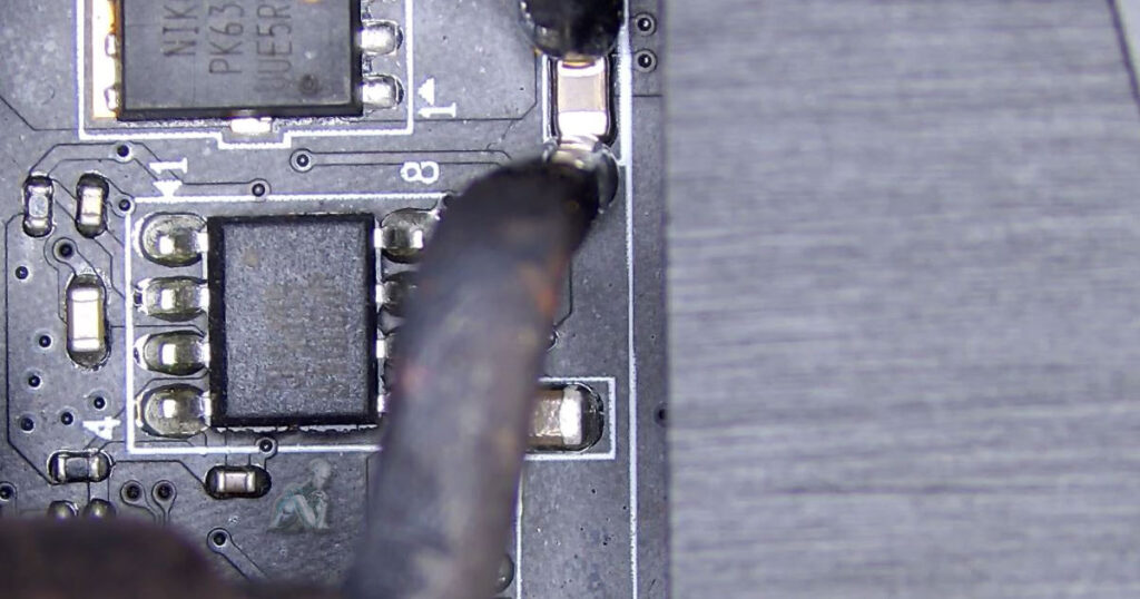 Rework process showing an SMD capacitor being lifted from a motherboard using heat and precision tools, with exposed pads and nearby components intact