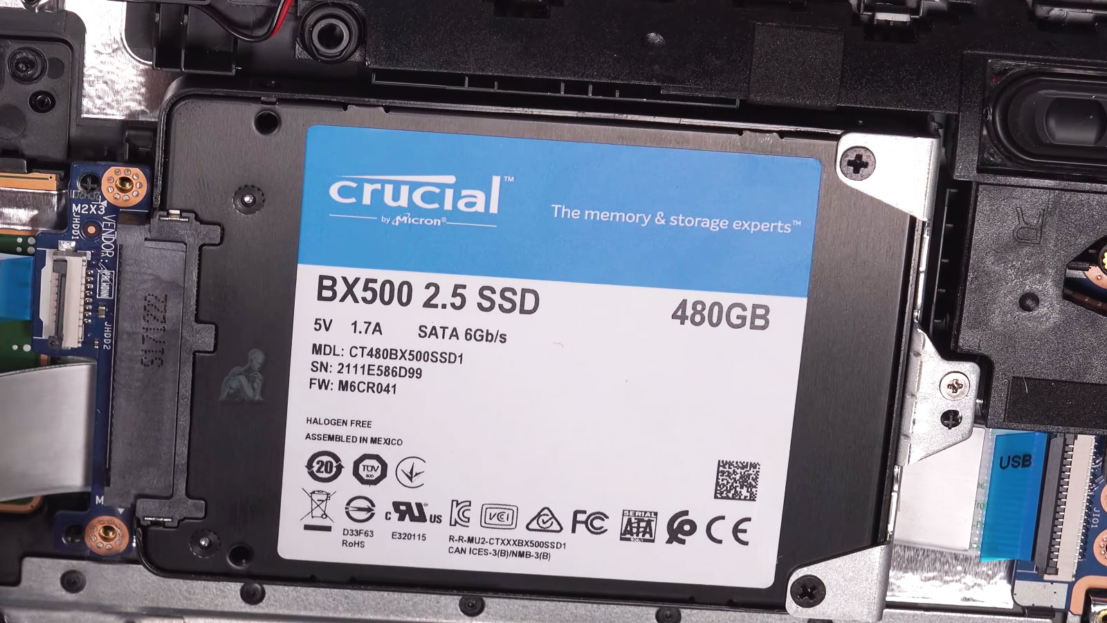 Crucial BX500 480GB SSD being installed inside an open laptop during storage upgrade