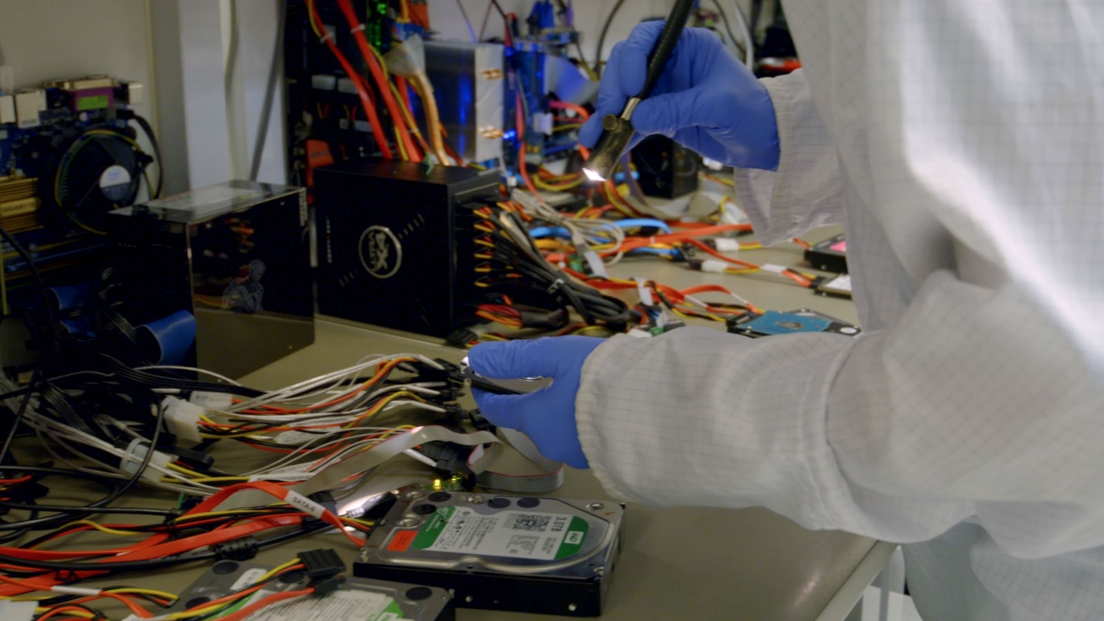 Data recovery technician inspecting an opened hard drive in a cleanroom environment in Miami