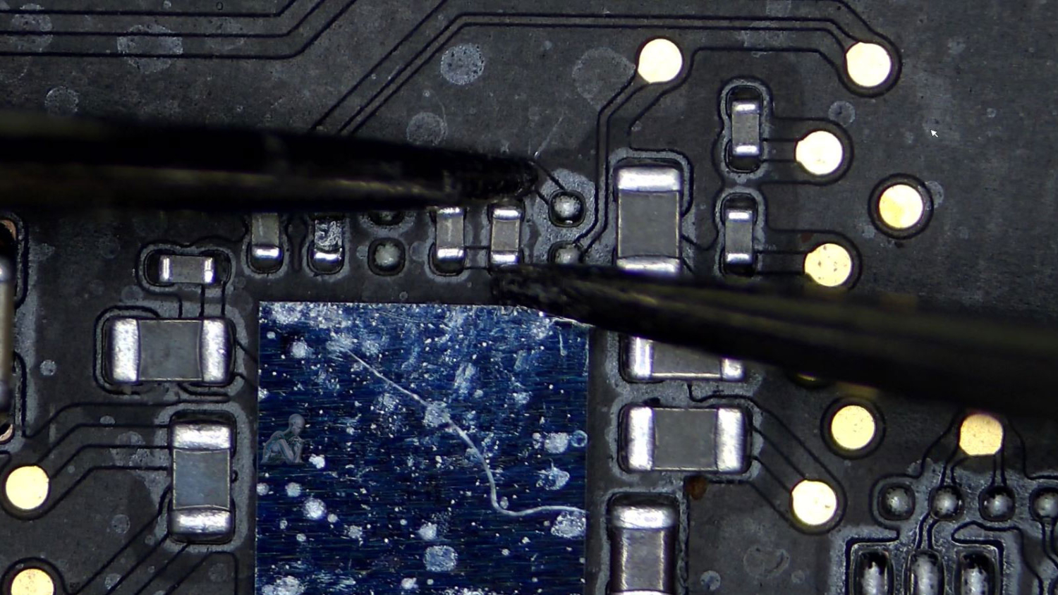 Technician measuring SMD capacitor on laptop motherboard using multimeter during circuit board diagnostic