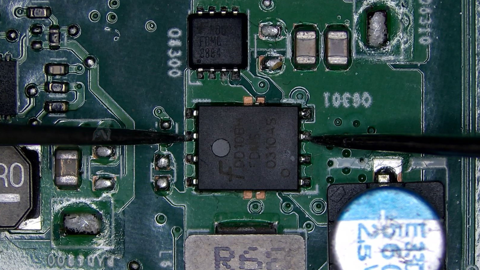 Multimeter probes testing both sides of a MOSFET on a laptop motherboard to check for a short circuit