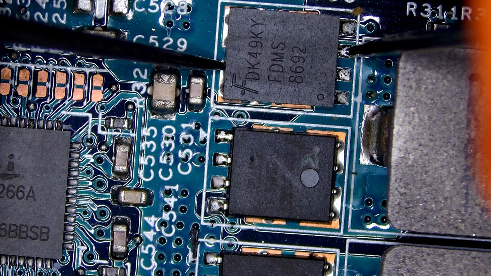 Laptop-Motherboard-MOSFET-Testing-with-Multimeter Technician using multimeter probes to test a MOSFET on a laptop motherboard for a possible short circuit