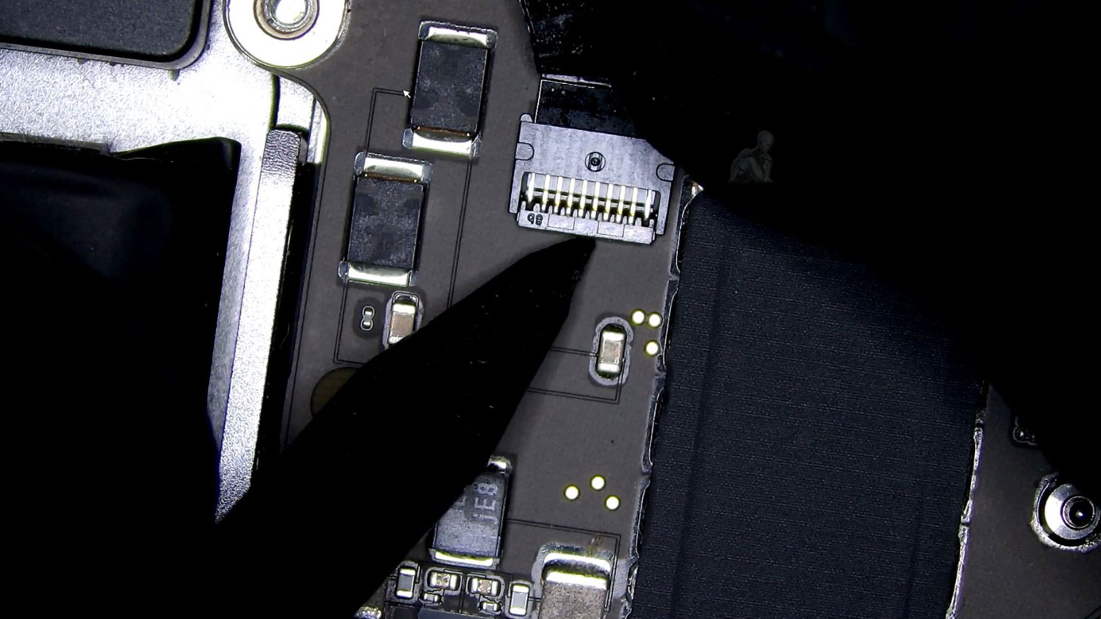 Technician disconnecting MacBook Pro fan cable from logic board connector during repair