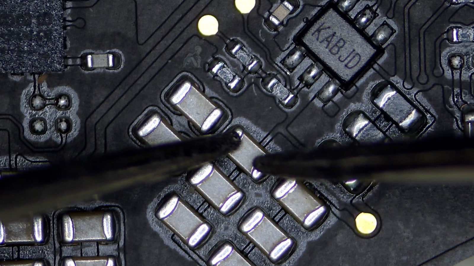 Technician testing MacBook Pro motherboard capacitors with multimeter for short circuit diagnosis