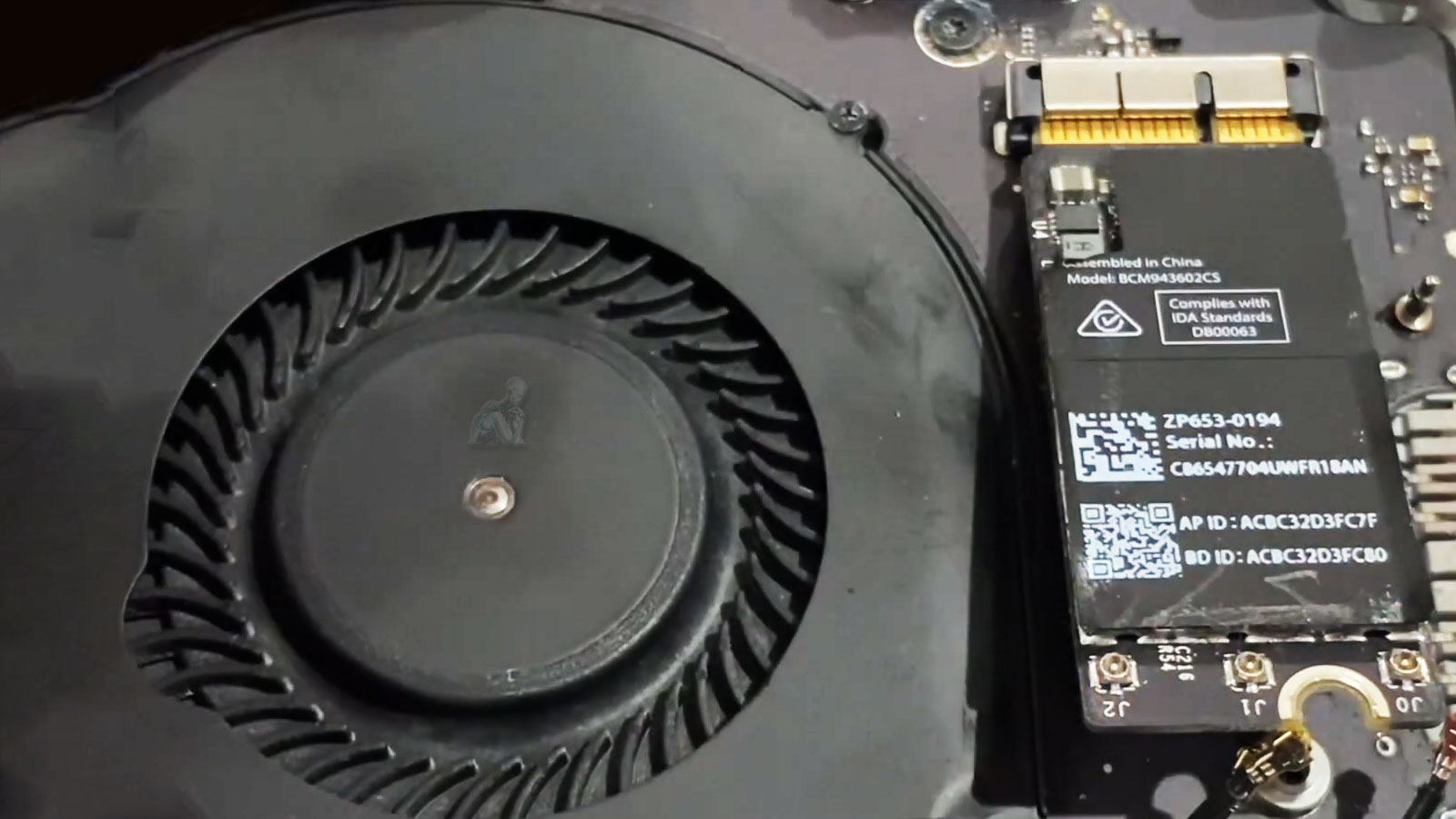 Technician disconnecting MacBook Pro Wi-Fi card connector for removal and repair