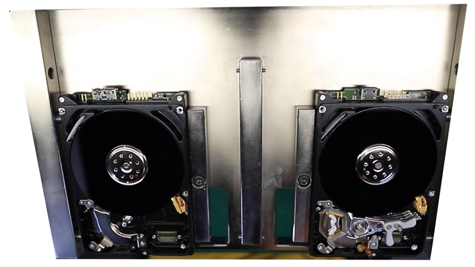 Open hard drives with exposed platters mounted on recovery equipment for data extraction