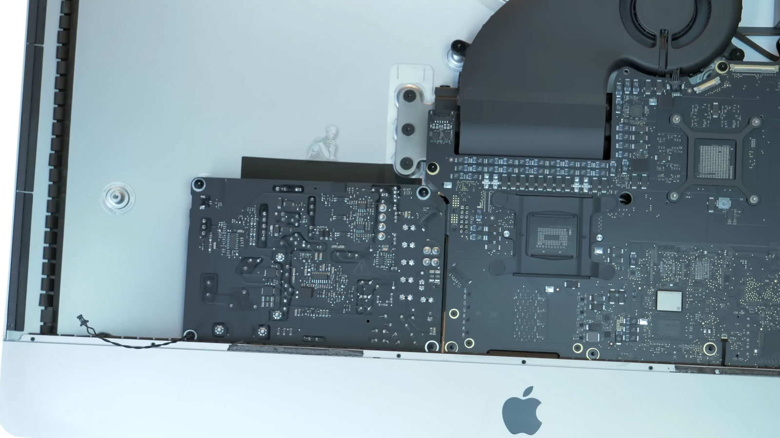 Open iMac with components removed showing power supply and logic board during repair preparation