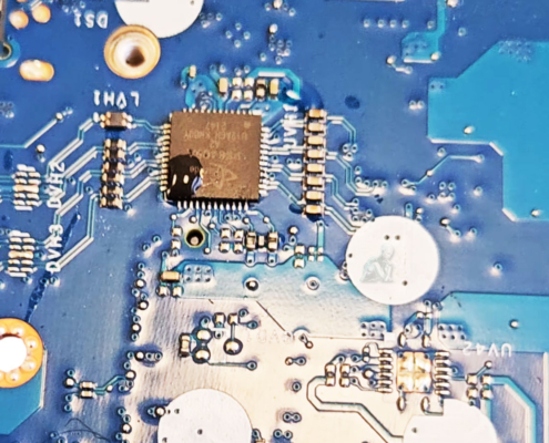 Laptop motherboard showing liquid damage and corrosion around an integrated circuit.